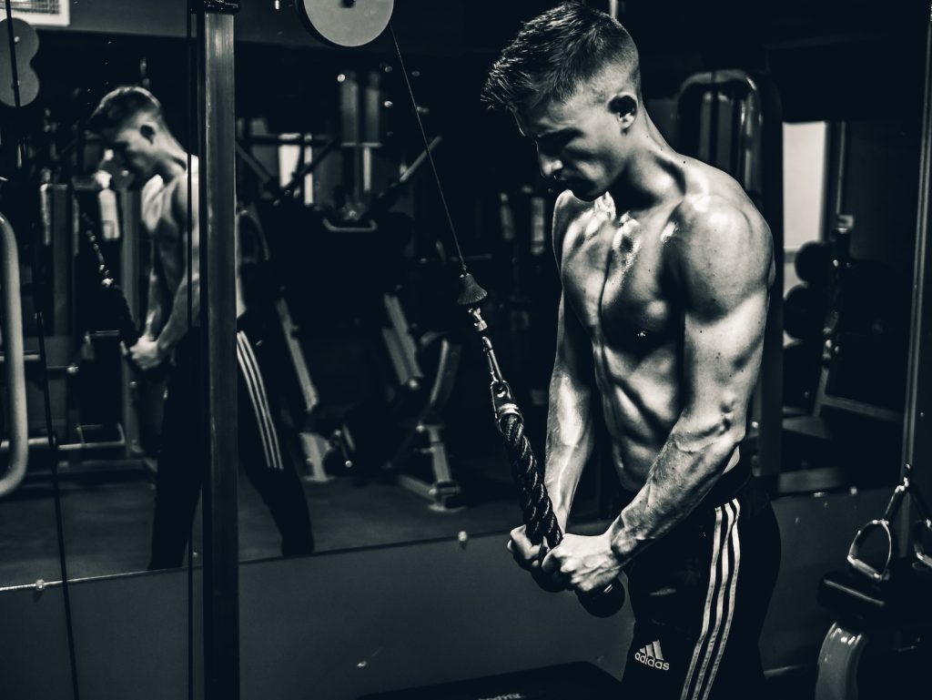 grayscale photo of man exercising triceps cable 