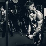 grayscale photo of man exercising triceps cable